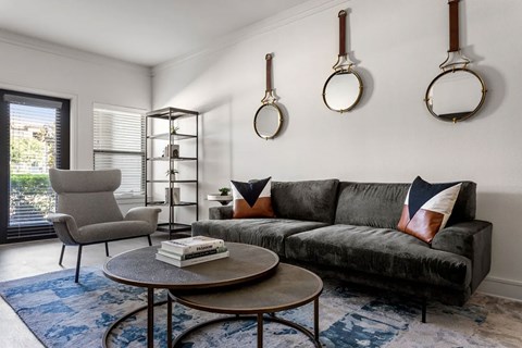 A living room with a grey couch, a grey chair, a coffee table, and a book on it.