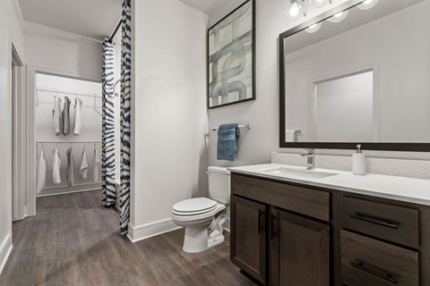 A bathroom with a toilet, sink, and a mirror.