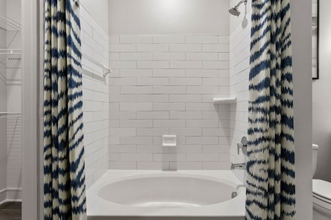 A white bathroom with a white tub and a shower curtain.