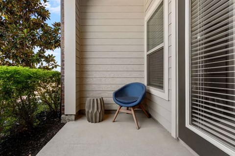 A blue chair sits on a porch next to a planter.
