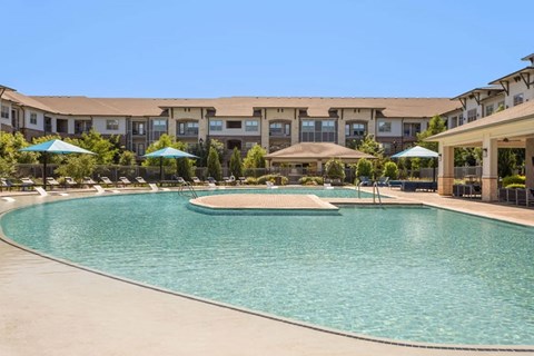 A large swimming pool in front of a building with a clear blue sky.