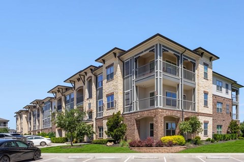 A large apartment building with a parking lot in front.