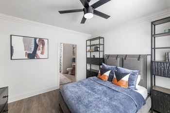 A bedroom with a bed, a ceiling fan, and a picture on the wall.