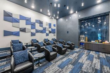 A modern lounge area with black leather chairs and a blue and white carpet.