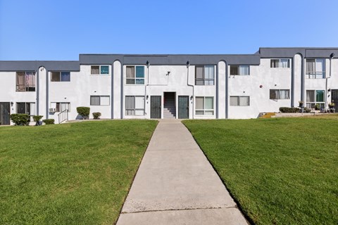 A long white building with a walkway in front.