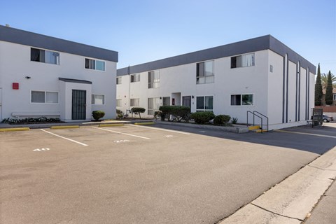 A parking lot in front of a white building with a clear blue sky.