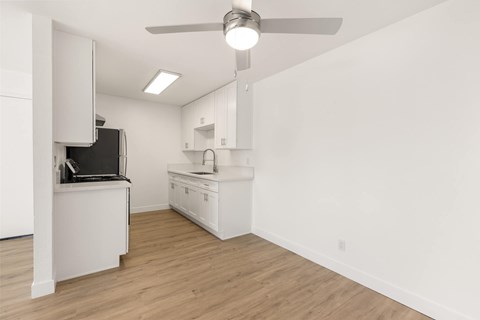 A kitchen with white cabinets and a black fridge.