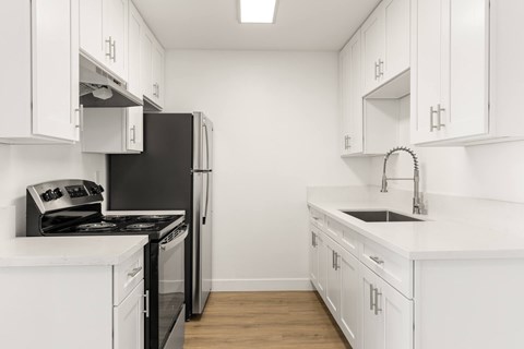A kitchen with white cabinets and a black refrigerator.