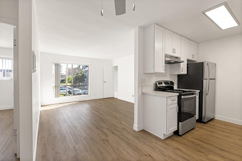 A kitchen with white cabinets and a black fridge.