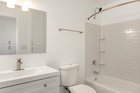 A white bathroom with a toilet, sink, and bathtub.