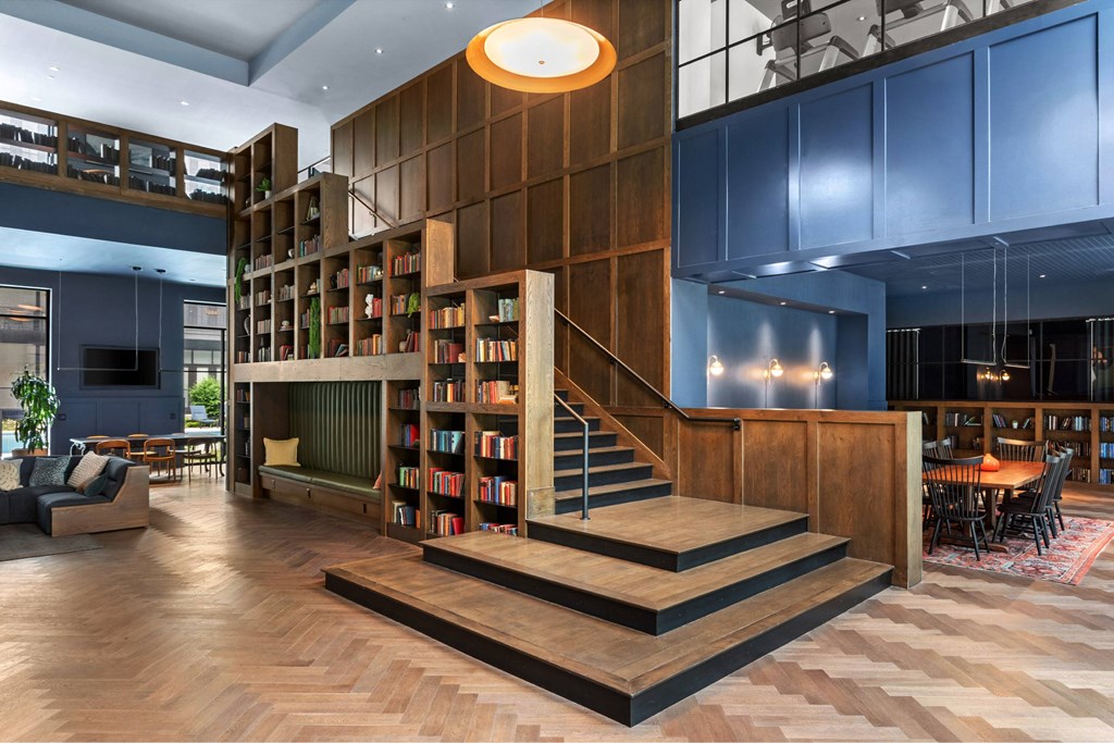 A modern living room with a staircase and bookshelves.