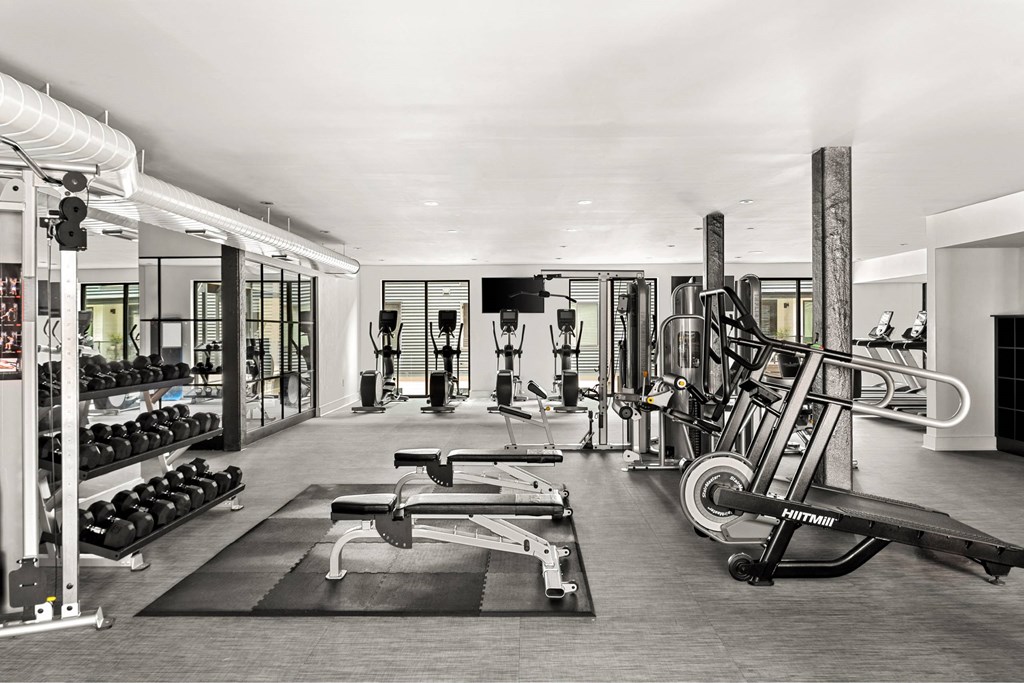 A black and white photo of a gym with a variety of equipment.