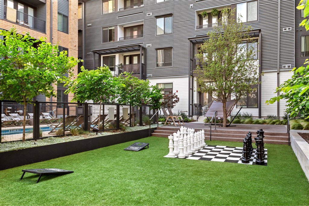 A chess set sits on a green lawn in front of a building.
