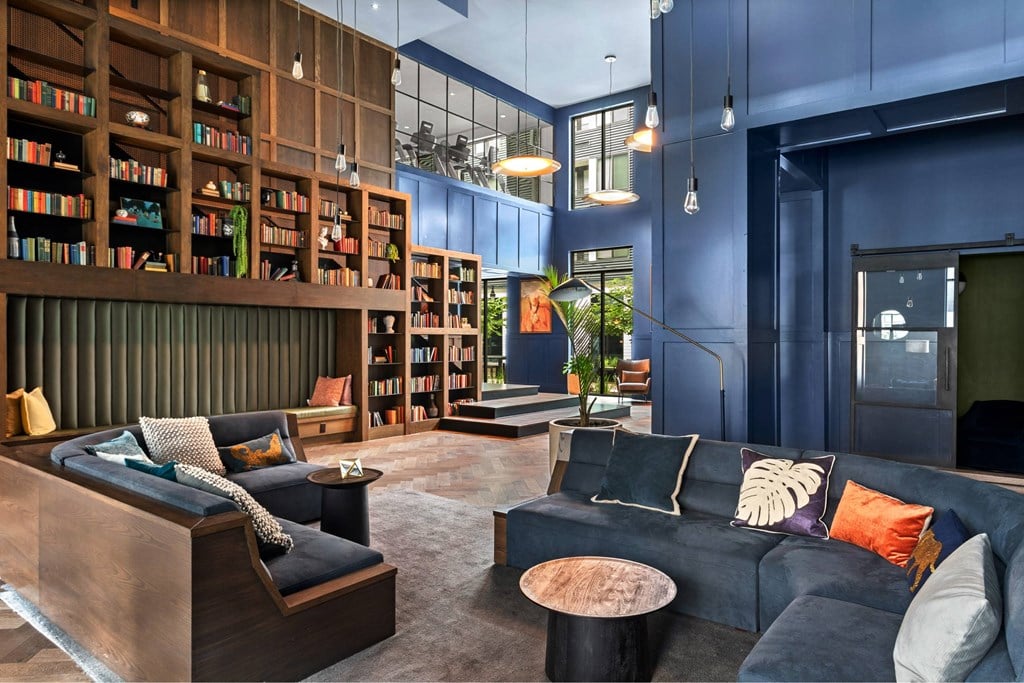 A modern living room with a dark blue couch and a wooden bookshelf.