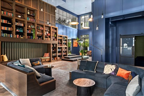 A modern living room with a dark blue couch and a wooden bookshelf.