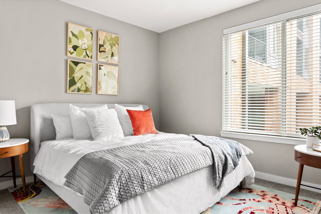 A bedroom with a large bed and a window with blinds.