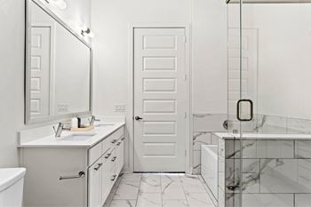 A white bathroom with a marble tub and a white door.