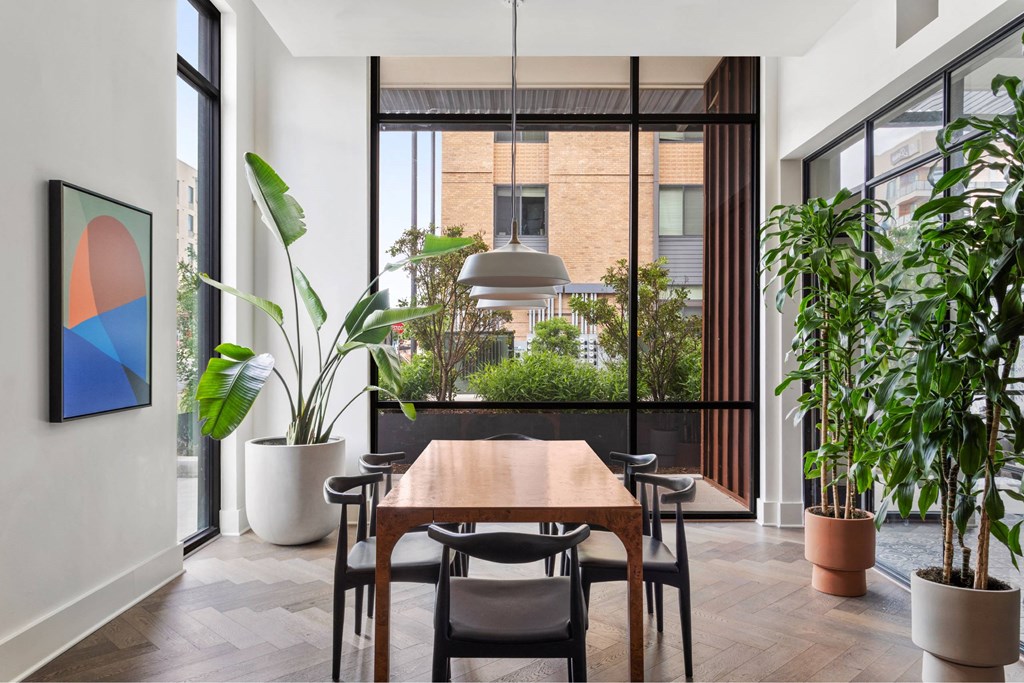 A dining room with a table and chairs and a potted plant.