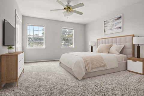 A bedroom with a large bed, a ceiling fan, and a window with a view of trees.