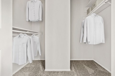 A white shirt hanging on a hanger in a white room.