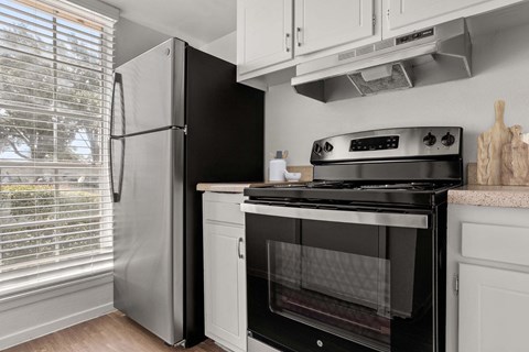 A black oven and stove top in a kitchen with white cabinets.
