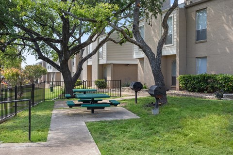 A tree with a green bench in front of a building.