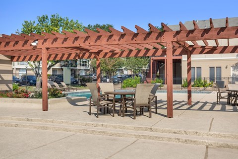 A patio with a table and chairs under a pergola.