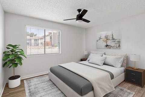 A bedroom with a bed, nightstand, and a plant.