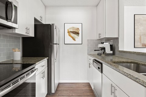 A kitchen with white cabinets and a black refrigerator.