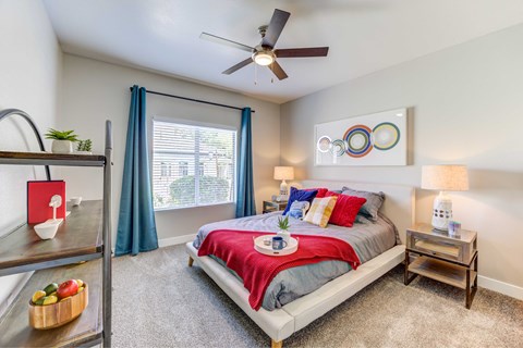 A bedroom with a bed, nightstand, and a fan.