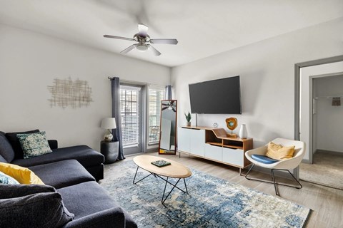 A living room with a blue rug and a black sofa.