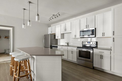 A kitchen with white cabinets and a grey island.