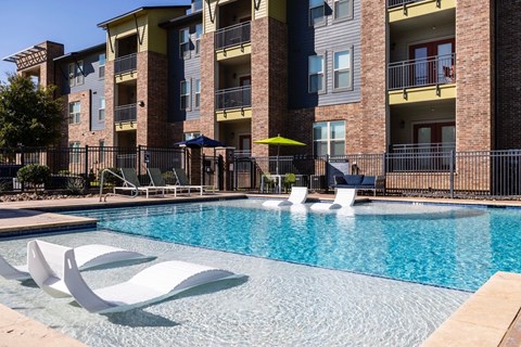 A pool surrounded by white chairs and a building in the background.