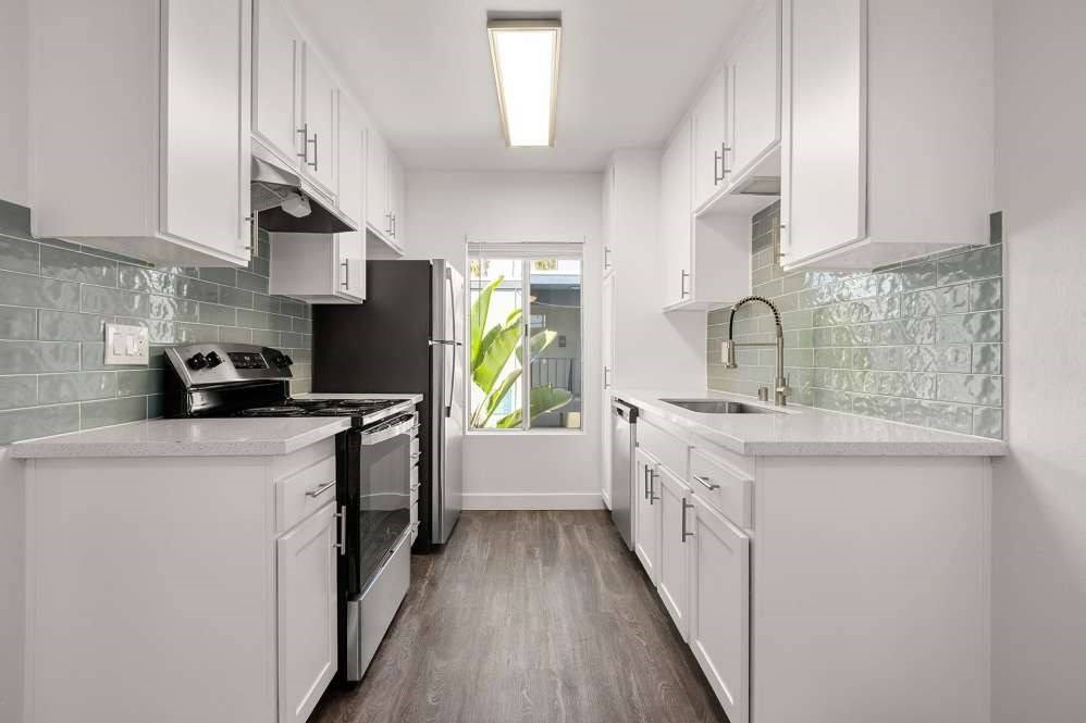 A kitchen with white cabinets and a black fridge.