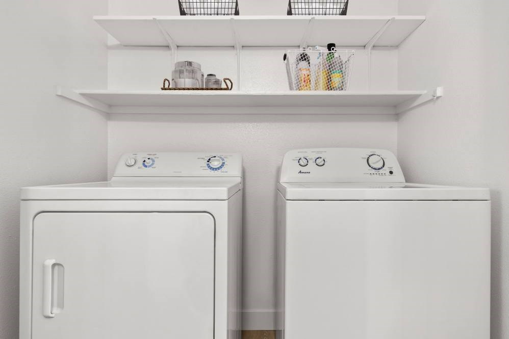 Two white front loading washing machines in a laundry room.