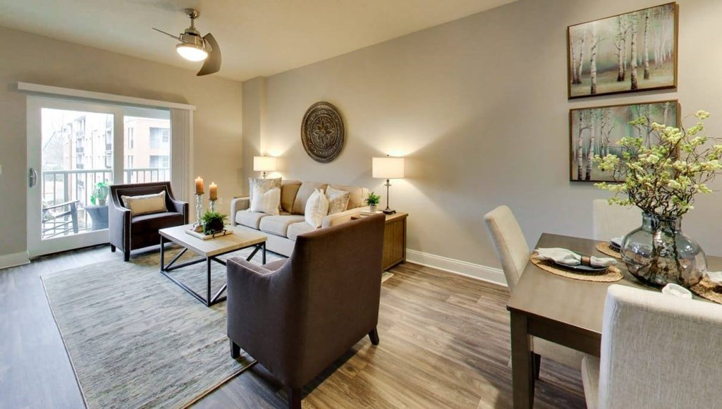 A living room with a brown couch, a coffee table, and a dining table with chairs.