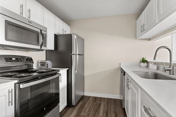 A kitchen with a black refrigerator and stove top oven.