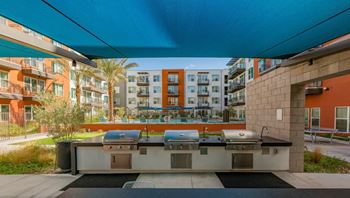 A modern outdoor kitchen area with a grill and sink.