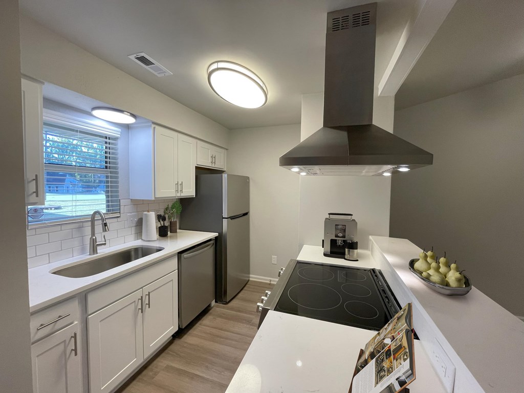 A modern kitchen with white cabinets and a black stove top.