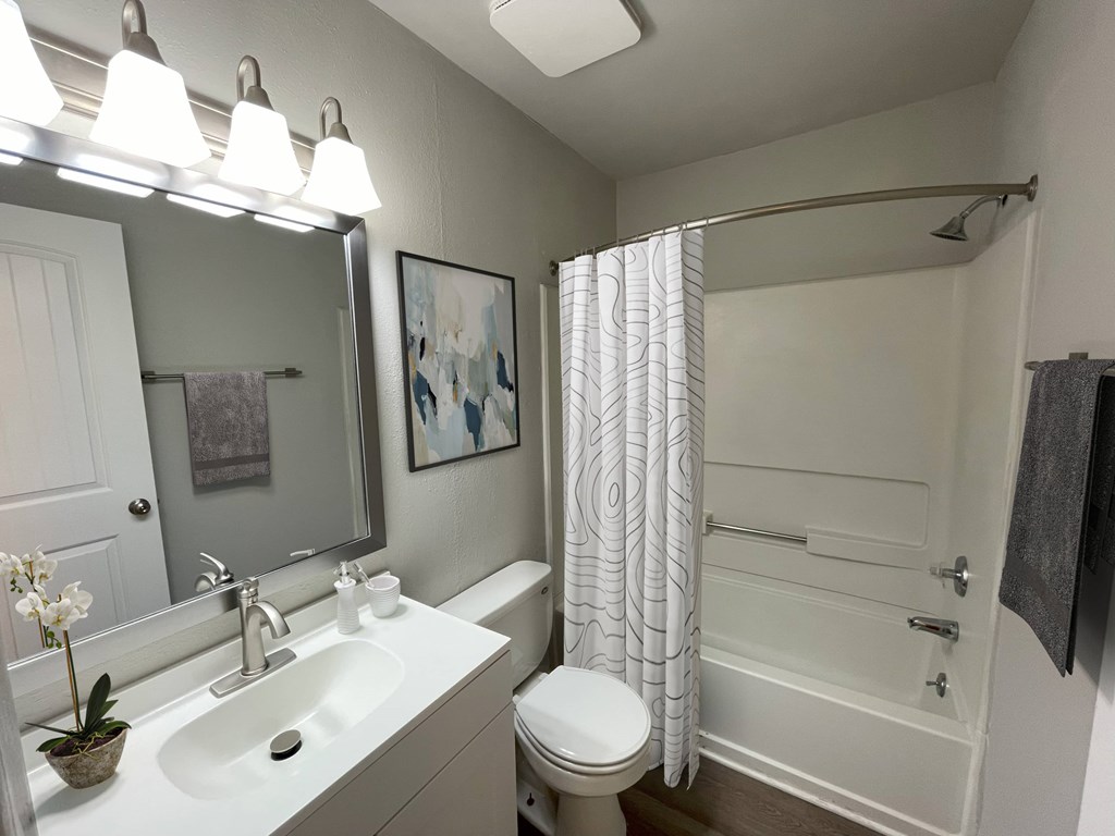 A white bathroom with a toilet, sink, and shower.