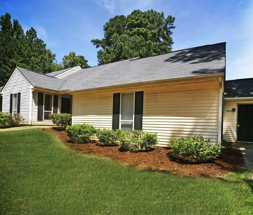 A house with a well-maintained lawn and a clear sky above.