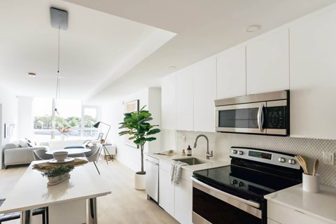 A modern kitchen with white cabinets and a black stove top oven.