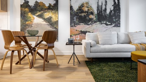 A living room with a white couch and a painting on the wall.