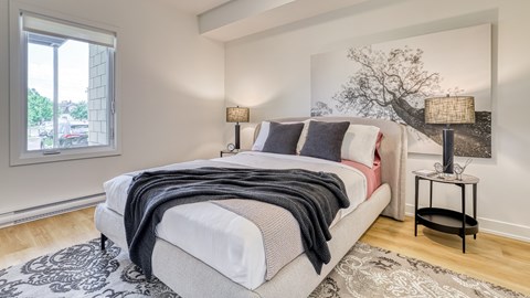 A bedroom with a large bed and a painting on the wall.