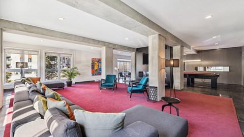 A living room with a red carpet and grey couches.