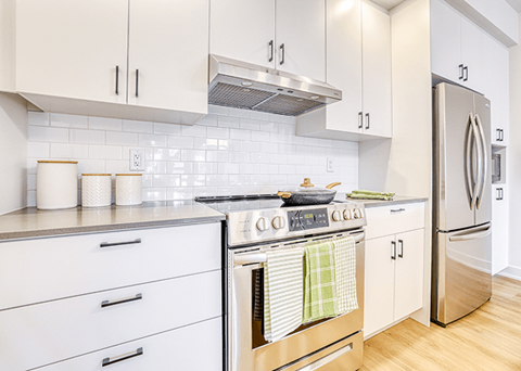 A kitchen with white cabinets and a stainless steel stove.