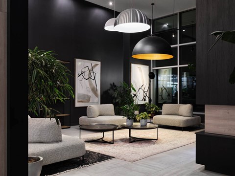 A modern living room with a grey sofa, a black and white lamp, and a large abstract painting on the wall.