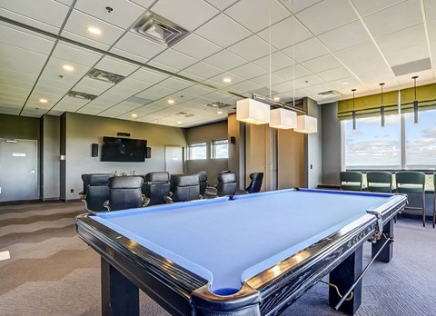 A pool table in a room with a television and chairs.