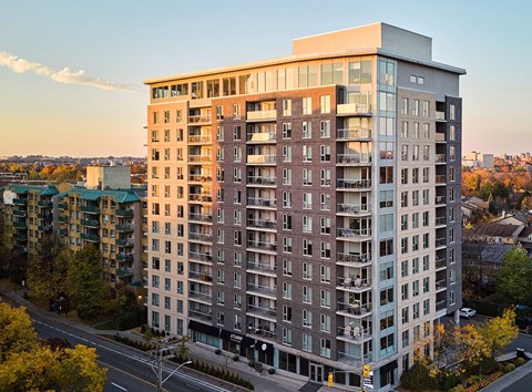 A tall apartment building with many windows and balconies is shown from an aerial perspective.