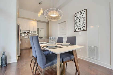 A dining room with a table set for two and a clock on the wall.